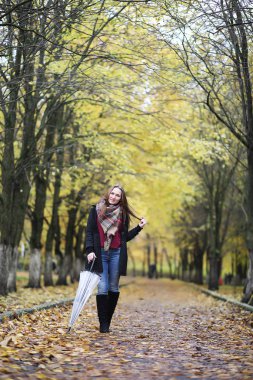 Genç kız sonbahar parkında yürüyüş yapıyor. 