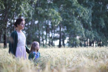 Genç anne yürüyerek buğday alanları içerisinde