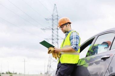 Kasklı ve üniformalı bir adam, sahada bir elektrikçi. Profesör.