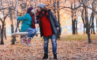 Kız sonbahar şehir parkında yaprak düşer. Genç güzel wi anne
