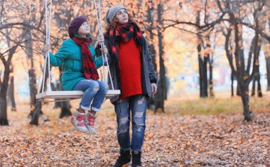 Kız sonbahar şehir parkında yaprak düşer. Genç güzel wi anne