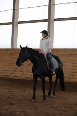 İnsanlar ahşap bir arenada at eğitiminde.