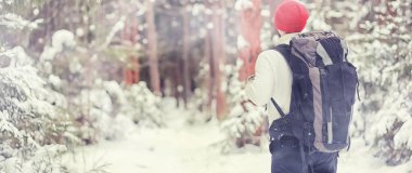 Bir adam sırt çantasıyla seyahat eder. Ormanda kış yürüyüşü. Touris