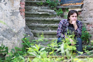 Adam terk edilmiş merdivenlerde oturuyor.