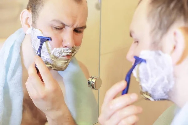 Um homem faz a barba na casa de banho pela manhã — Fotografia de Stock