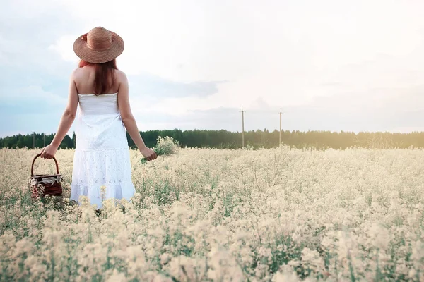 Chica en vestido blanco en un campo de flores amarillas floreciendo — Foto de Stock