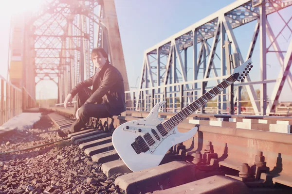 Ένας άνθρωπος με μια ηλεκτρική κιθάρα επί της σιδηροδρομικής γραμμής. Μουσικός σε ένα le — Φωτογραφία Αρχείου