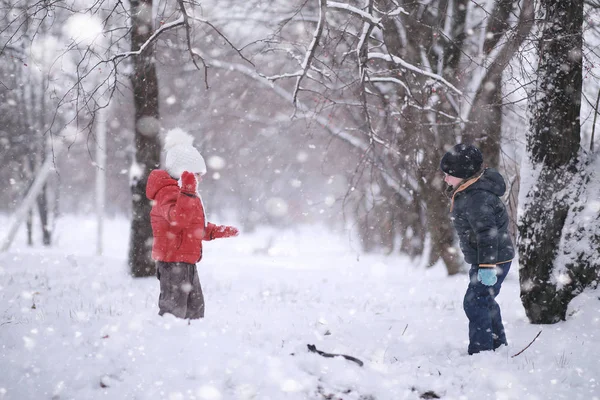 Los niños caminan en el parque primera nieve —  Fotos de Stock