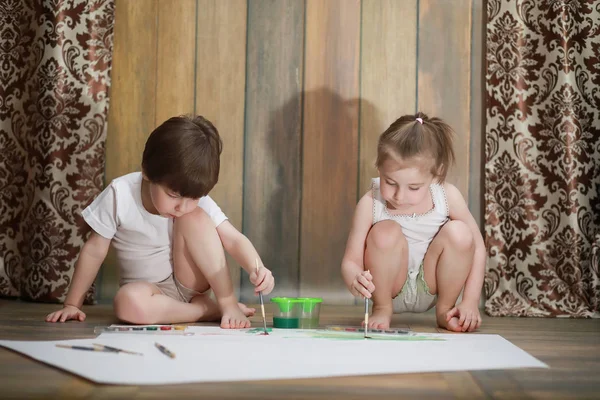Kleine Kinder malen auf ein großes Blatt Papier — Stockfoto