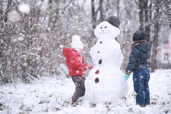 Kinder spazieren im Park im ersten Schnee — Stockfoto