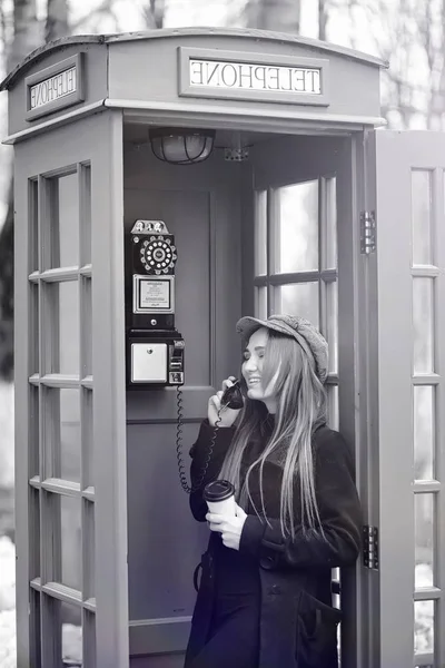 Menina bonita em uma cabine telefônica. A menina está falando no th — Fotografia de Stock