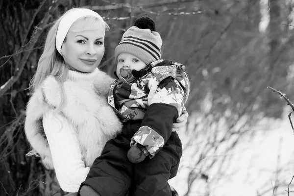 一个年轻的母亲走在一个冬天的一天, 怀里抱着一个孩子。 — 图库照片