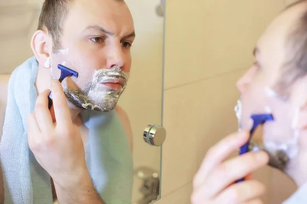 Um homem faz a barba na casa de banho pela manhã — Fotografia de Stock