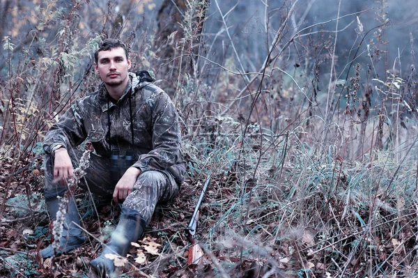 Чоловік в камуфляжі і з мисливською гвинтівкою в лісі на шпилі — стокове фото