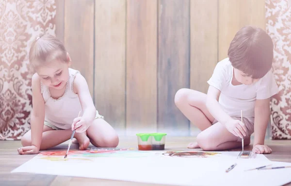 Pequenas crianças pintam em uma grande folha de papel — Fotografia de Stock