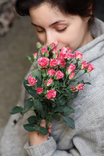 ブッシュの背景に女性の手にはバラの花束 — ストック写真