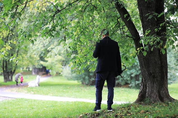 Молодий чоловік в окулярах гуляє в парку з парасолькою під час — стокове фото