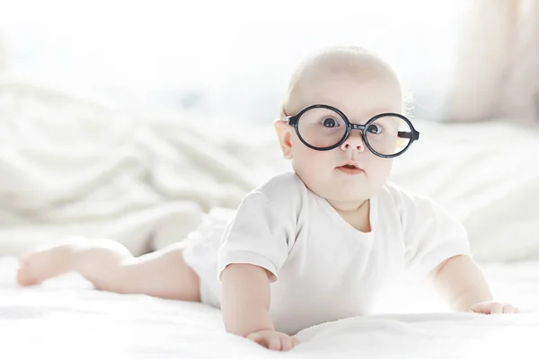 Um bebê recém-nascido está deitado em uma cama macia em óculos . — Fotografia de Stock