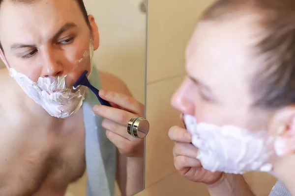 Um homem faz a barba na casa de banho pela manhã — Fotografia de Stock