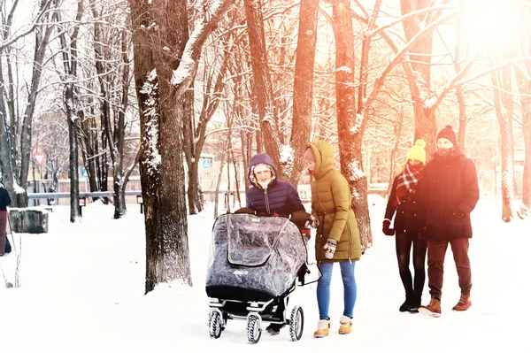 friends with stroller walking in snowy winter park