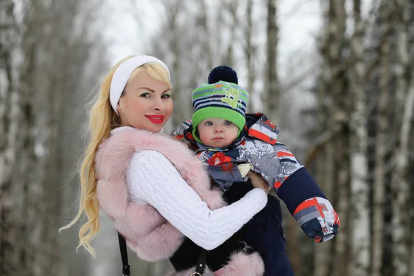 Mladá maminka chodí na zimní den s dítětem v náručí v th — Stock fotografie