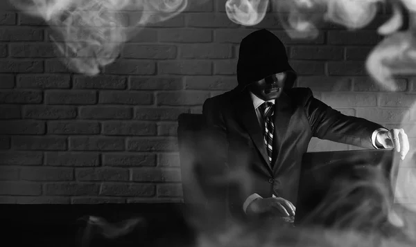 Hacker i svart mask och huva vid bordet — Stockfoto