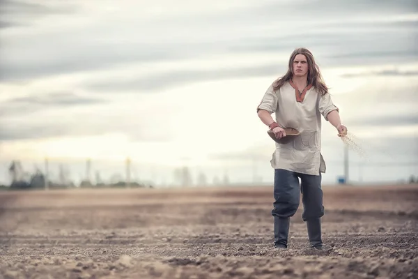 A young peasant sows the field with grain — Stock Photo, Image