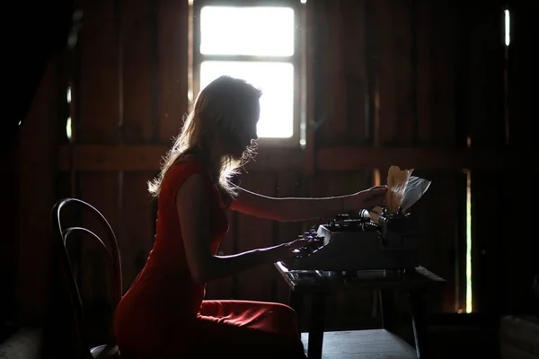 Une fille au style rétro imprime sur une vieille machine à écrire — Photo