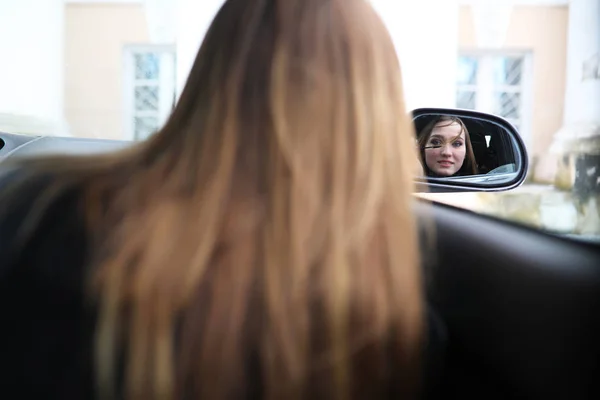 Menina fazendo maquiagem olhando no espelho retrovisor — Fotografia de Stock