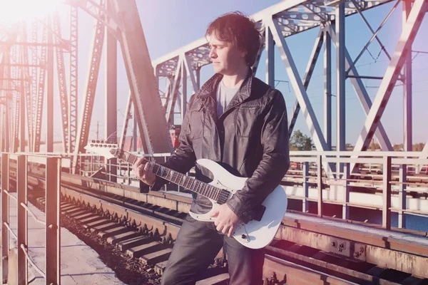 Um homem com uma guitarra eléctrica na estrada de ferro. Um músico em uma le — Fotografia de Stock