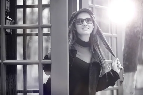 Menina bonita em uma cabine telefônica. A menina está falando no th — Fotografia de Stock