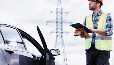 Kasklı ve üniformalı bir adam, sahada bir elektrikçi. Profesör.