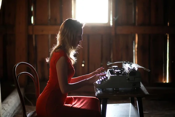 Una chica con estampados de estilo retro en una vieja máquina de escribir — Foto de Stock