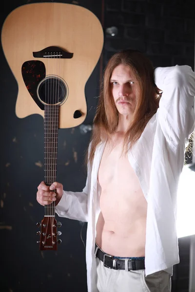 Młody człowiek z długimi włosami z gitarą — Zdjęcie stockowe