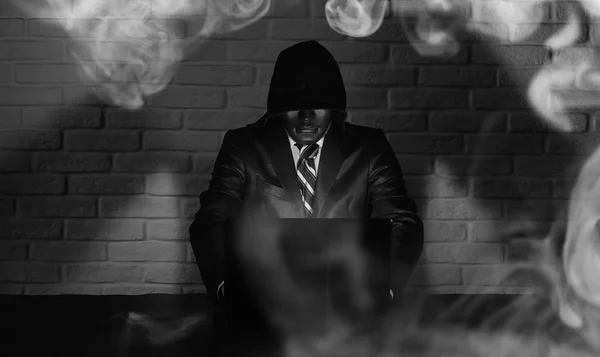 Haker w czarna maska i kaptur na stole — Zdjęcie stockowe