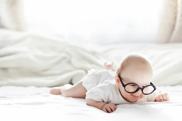 A newborn baby is lying on a soft bed in glasses. — Stock Photo, Image