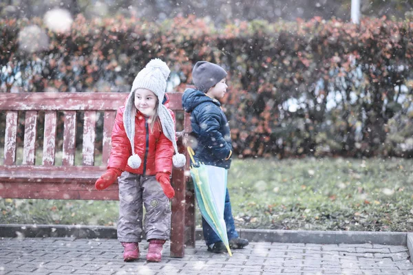 Dzieci chodzą w parku pierwszy śnieg — Zdjęcie stockowe