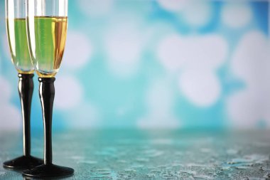 Köpüklü şaraplar için uzun bardaklı bir arka plan. Cam bardaklarda şampanya spreyi. Yansımalı kutlama içkisi.