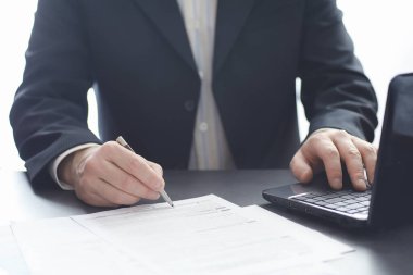 Müdür ofisteki bir dizüstü bilgisayarda çalışıyor. İşadamı çevrimiçi işlem yapıyor. Değiş tokuş internet üzerinden yapılıyor..
