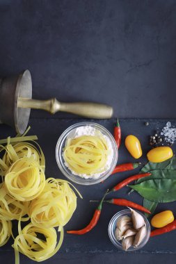 Baharatlı ve sebzeli makarna. Siyah taş üzerinde yemek pişirmek için sebzeli erişte..