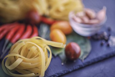 Baharatlı ve sebzeli makarna. Siyah taş üzerinde yemek pişirmek için sebzeli erişte..