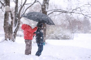 Çocuklar parkta ilk karla yürür.