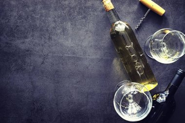 Masada bir bardak kırmızı şarap. Siyah şişe ve bir bardak şarap..