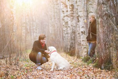 Sonbahar bahçesinde annesiyle köpek gezintisine çıkmış genç bir kız.