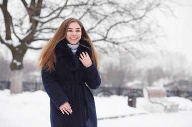 Kış parkında yürüyüş yapan genç bir kız. Kış ormanlarında Noel tatili. Kız parkta kışın tadını çıkarıyor.