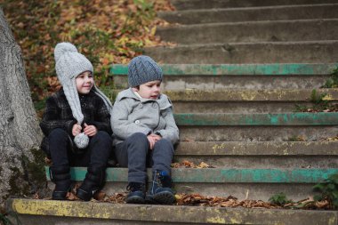 Çocuklar sonbaharda sonbahar parkında yürür