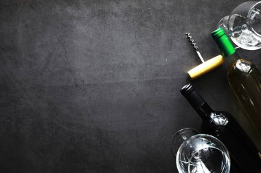 Masada bir bardak kırmızı şarap. Siyah şişe ve bir bardak şarap..