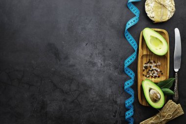 Avokado yemek tarifleri. Tahta kesme tahtasında servis edilen olgun yeşil avokado..