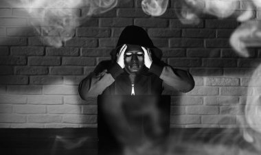 Siyah maskeli ve başlıklı bilgisayar korsanı Monito 'nun önündeki masada.