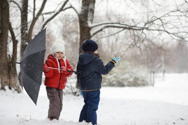 Kışın parktaki çocuklar sno ile oynarlar.